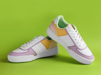 Photo of Pair of comfortable sports shoes on light green background