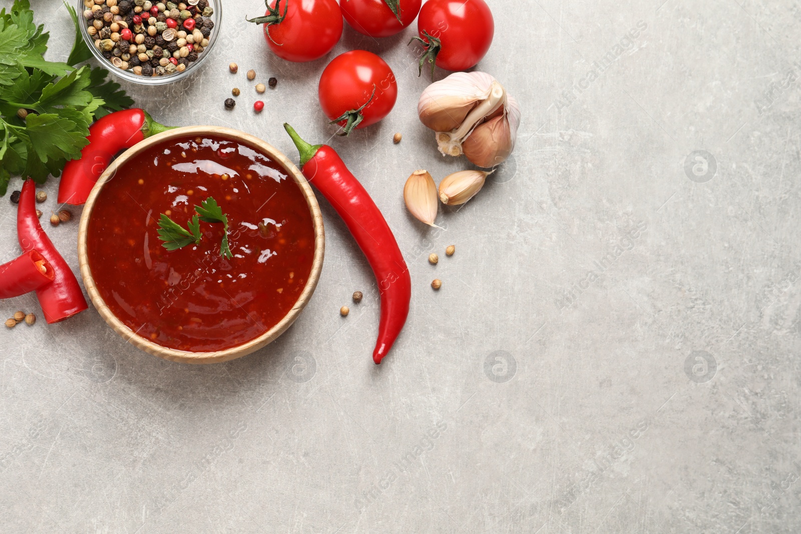 Photo of Spicy chili sauce and ingredients on light grey table, flat lay. Space for text