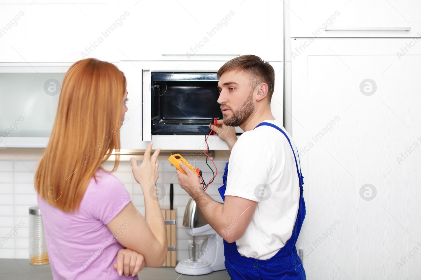 Photo of Housewife and repairman near microwave oven in kitchen