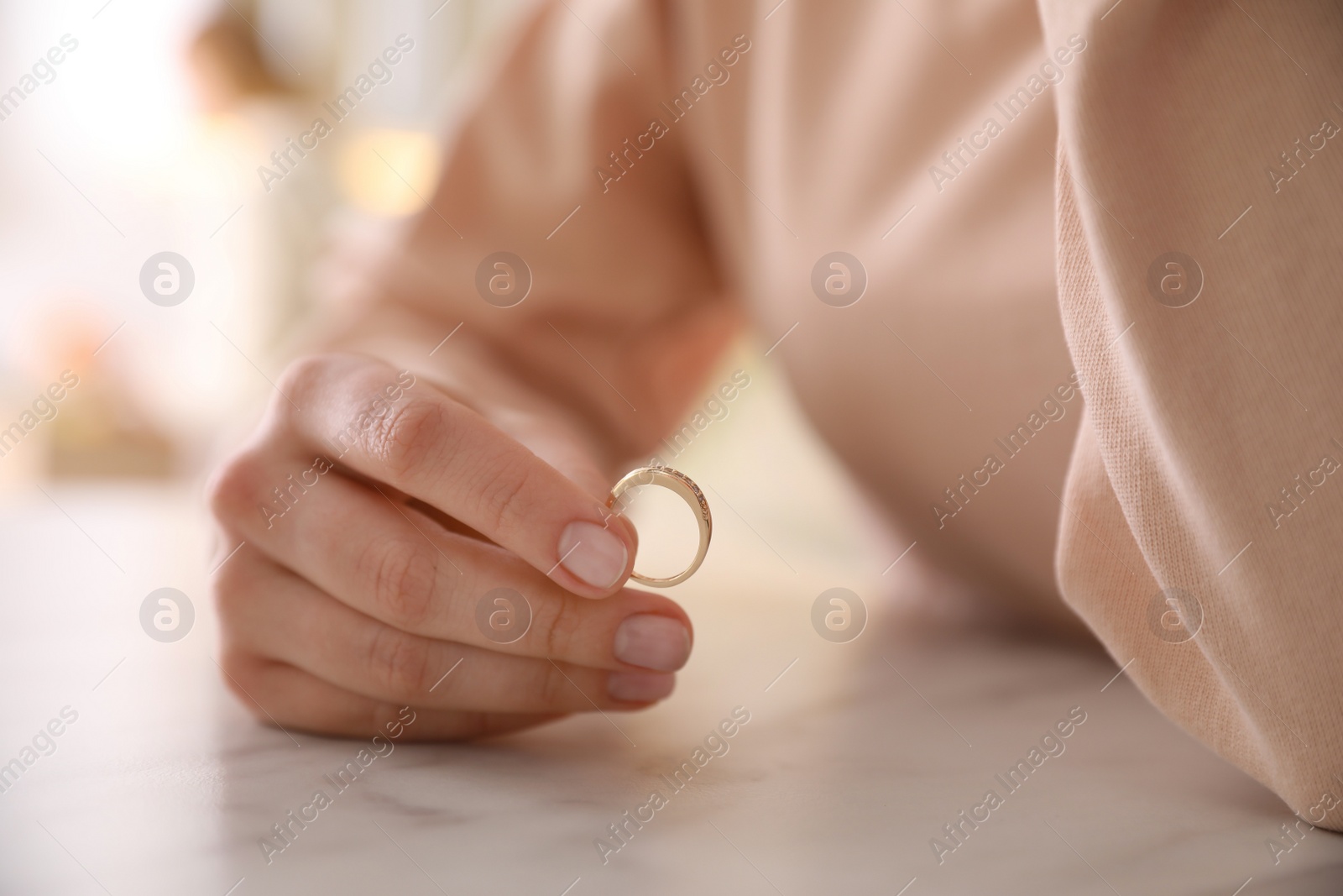 Photo of Woman holding wedding ring at table indoors, closeup. Divorce concept