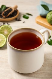 Cup of tasty bergamot tea on white wooden table, closeup