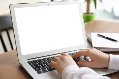 Young woman using modern computer at table in office, closeup. Space for design