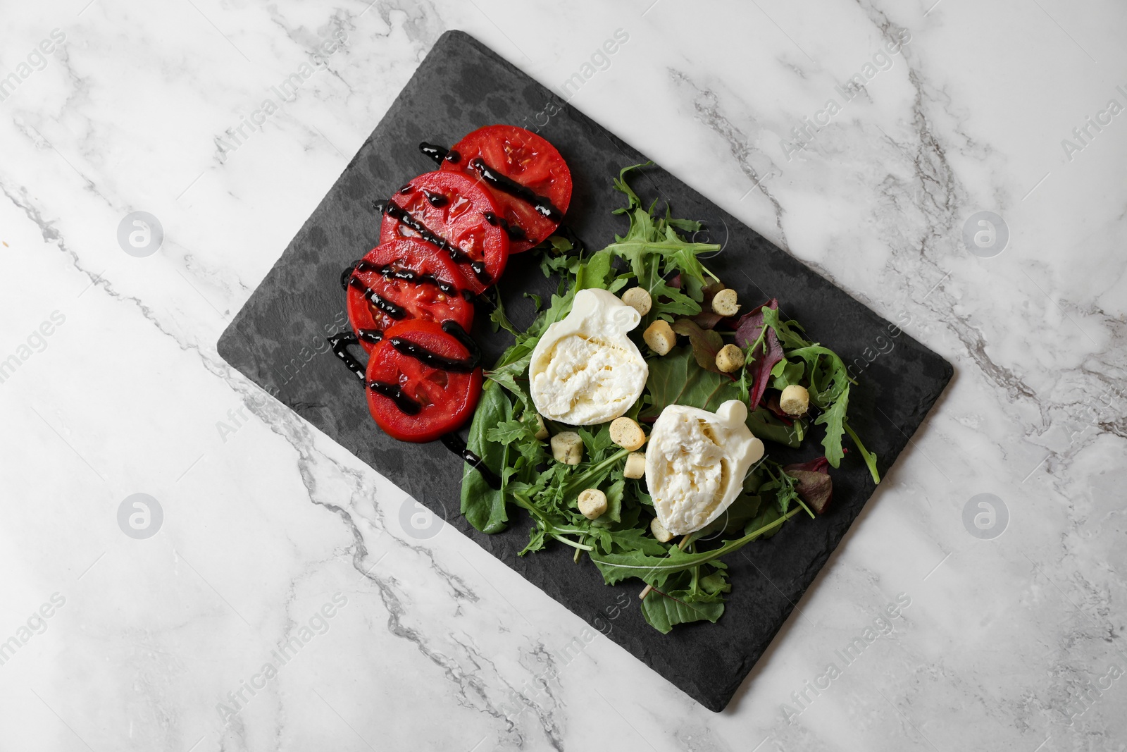 Photo of Delicious burrata cheese, tomatoes and arugula on white marble table, top view