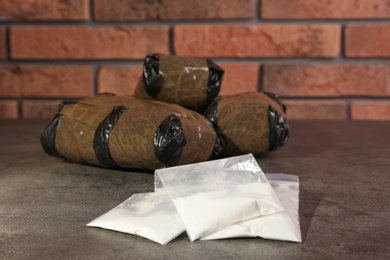 Hemp and cocaine in packages on grey table. Drug addiction