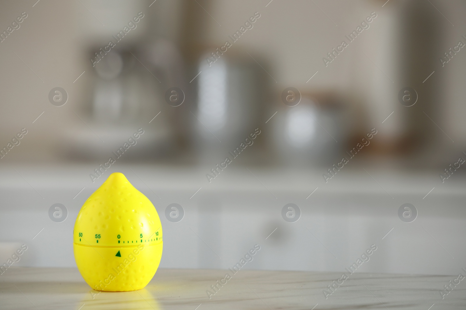 Photo of Kitchen timer in shape of lemon on white marble table against blurred background. Space for text