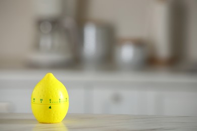 Photo of Kitchen timer in shape of lemon on white marble table against blurred background. Space for text