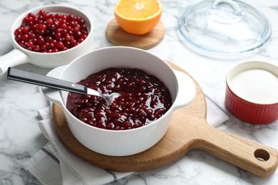 Photo of Fresh cranberry sauce in bowl served on white marble table, closeup