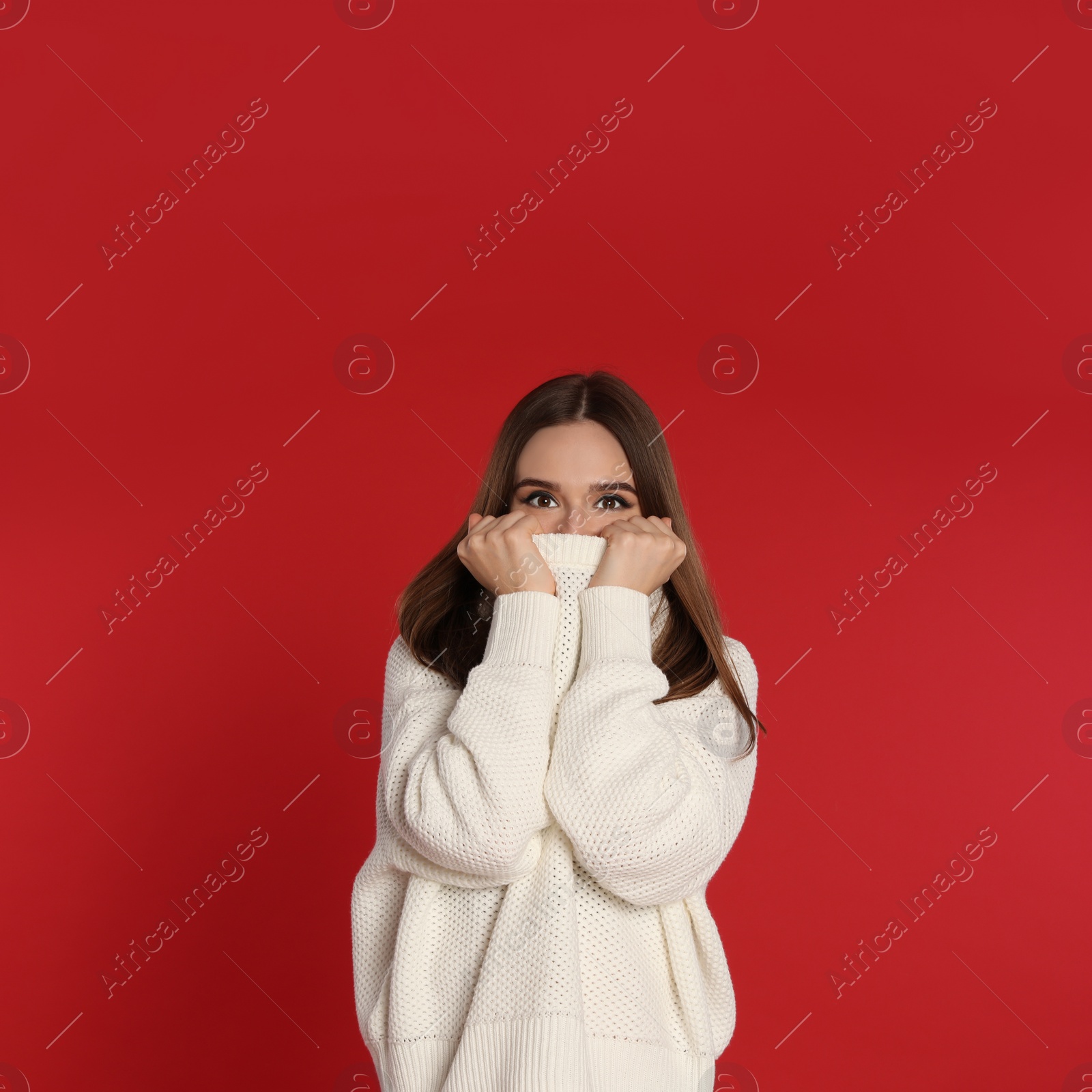 Photo of Beautiful young woman in white sweater on red background. Winter season