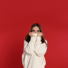 Photo of Beautiful young woman in white sweater on red background. Winter season