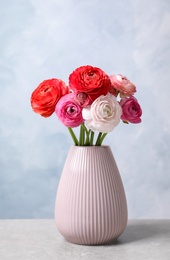Photo of Beautiful fresh ranunculus flowers in vase on white table near color wall