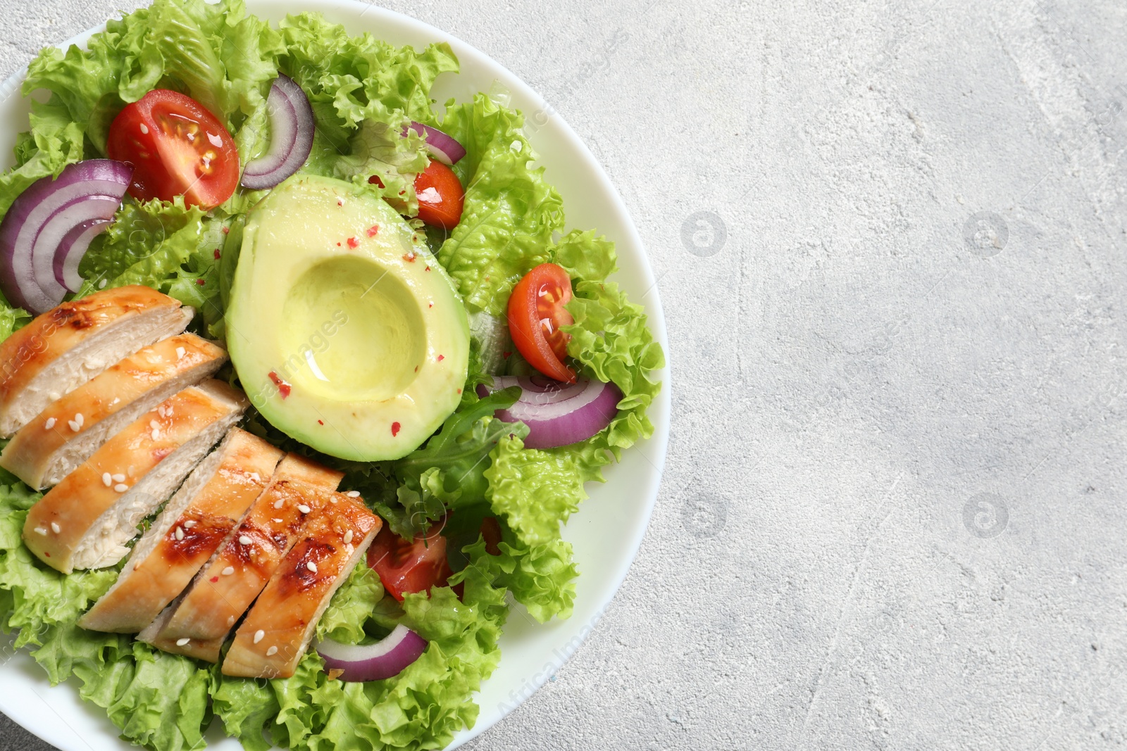 Photo of Delicious salad with chicken, avocado and vegetables on light grey table, top view. Space for text