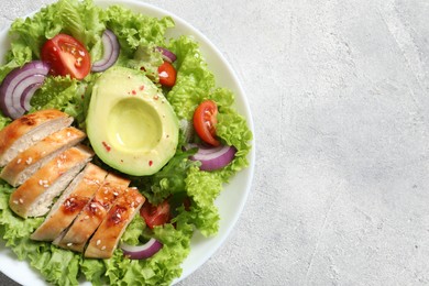 Delicious salad with chicken, avocado and vegetables on light grey table, top view. Space for text