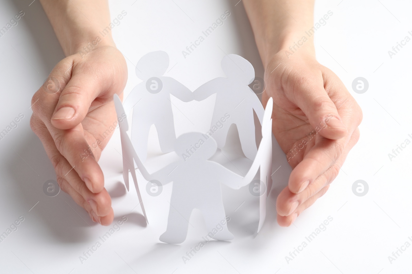 Photo of Young woman protecting paper people on light background. Unity concept