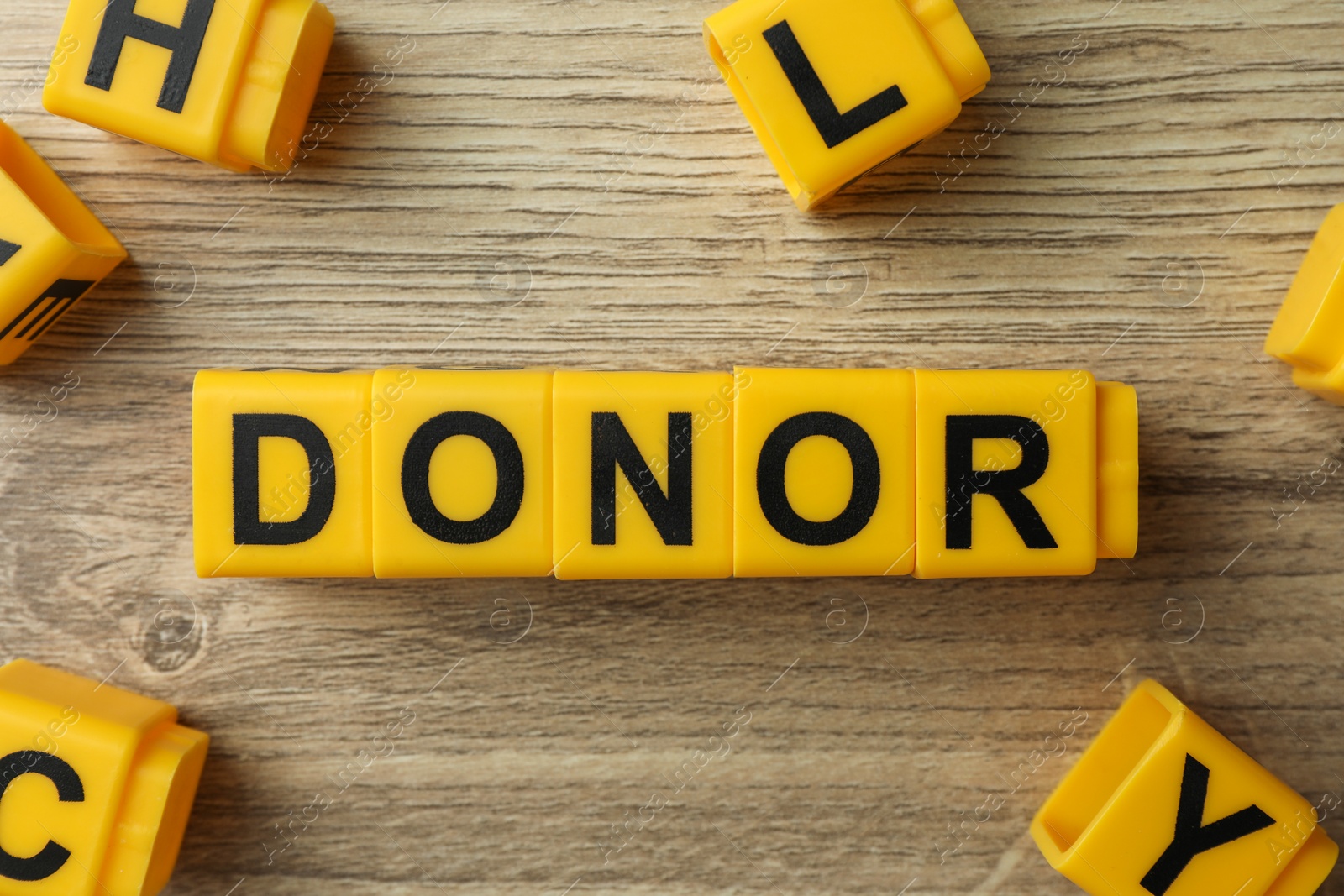 Photo of Word Donor made of yellow cubes on wooden table, flat lay