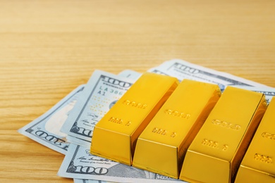Gold bars and dollar bills on table, closeup. Space for text