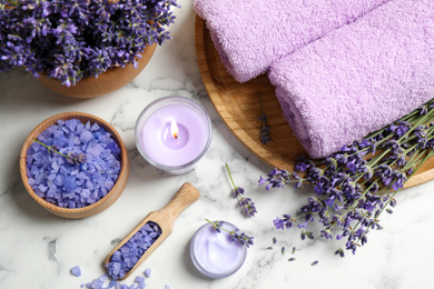 Cosmetic products and lavender flowers on white marble table, flat lay