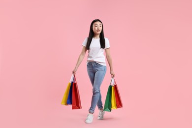 Beautiful woman with shopping bags on pink background