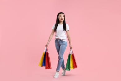 Photo of Beautiful woman with shopping bags on pink background