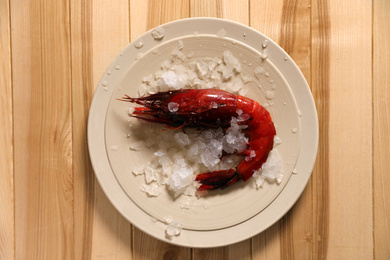 Photo of Fresh carabinero shrimp with ice on wooden table, top view