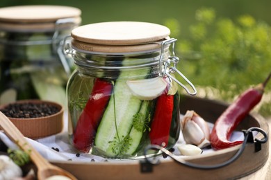 Photo of Jar of delicious pickled cucumbers and ingredients on table, closeup
