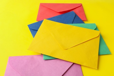 Photo of Colorful paper envelopes on yellow background. Mail service