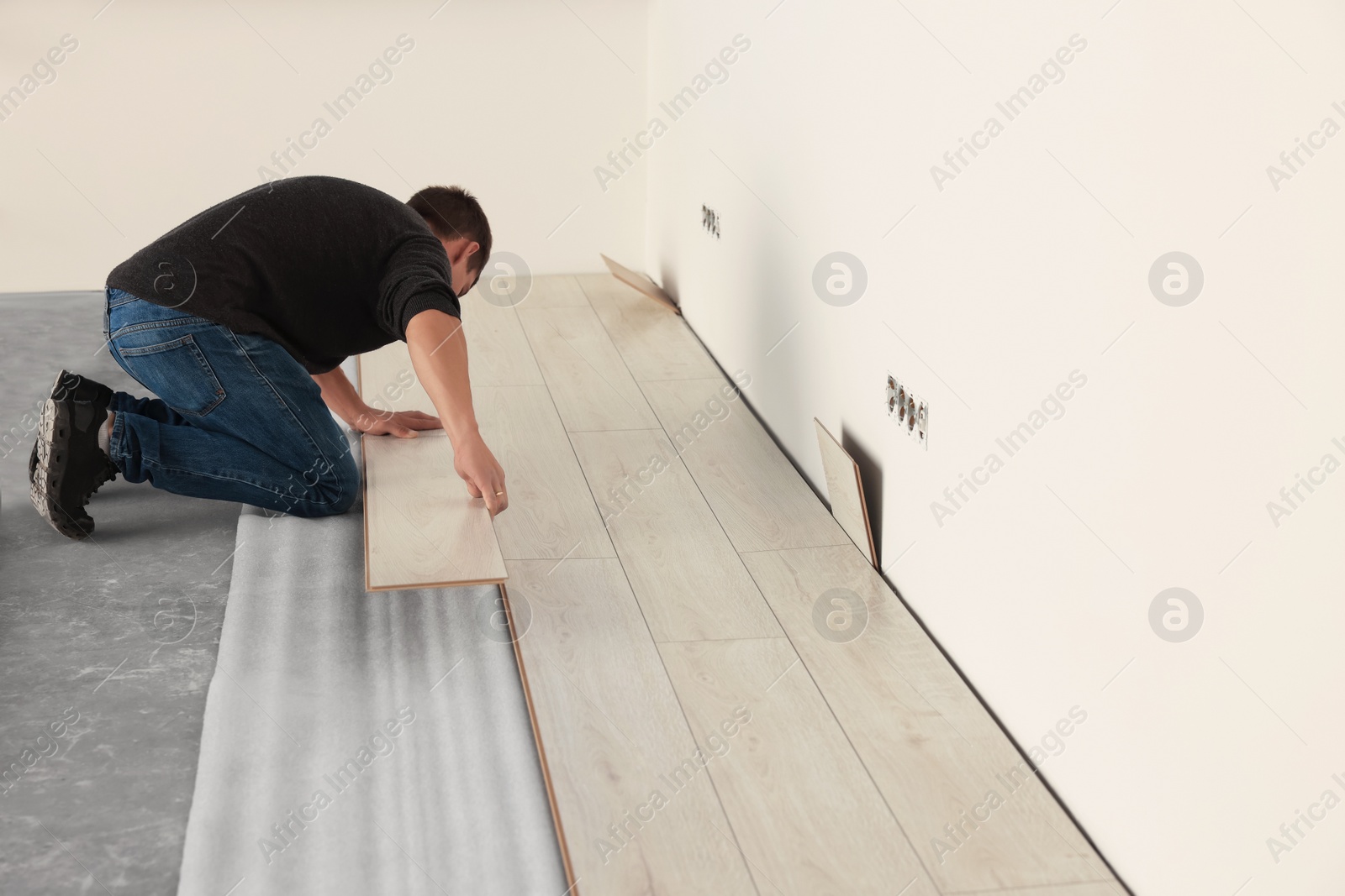 Photo of Professional worker installing new laminate flooring. Space for text