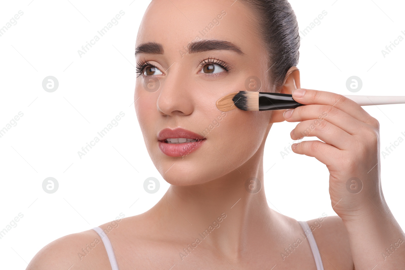 Photo of Woman applying foundation on face with brush against white background