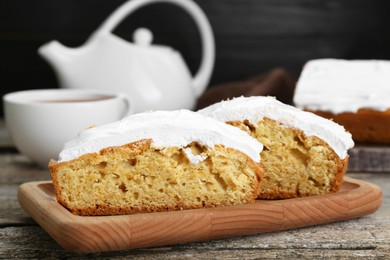 Photo of Pieces of homemade yogurt cake with cream on wooden table, closeup