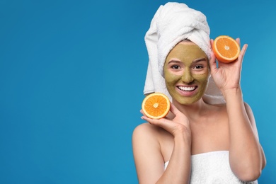 Photo of Beautiful woman with mask on face and cut orange against color background. Space for text