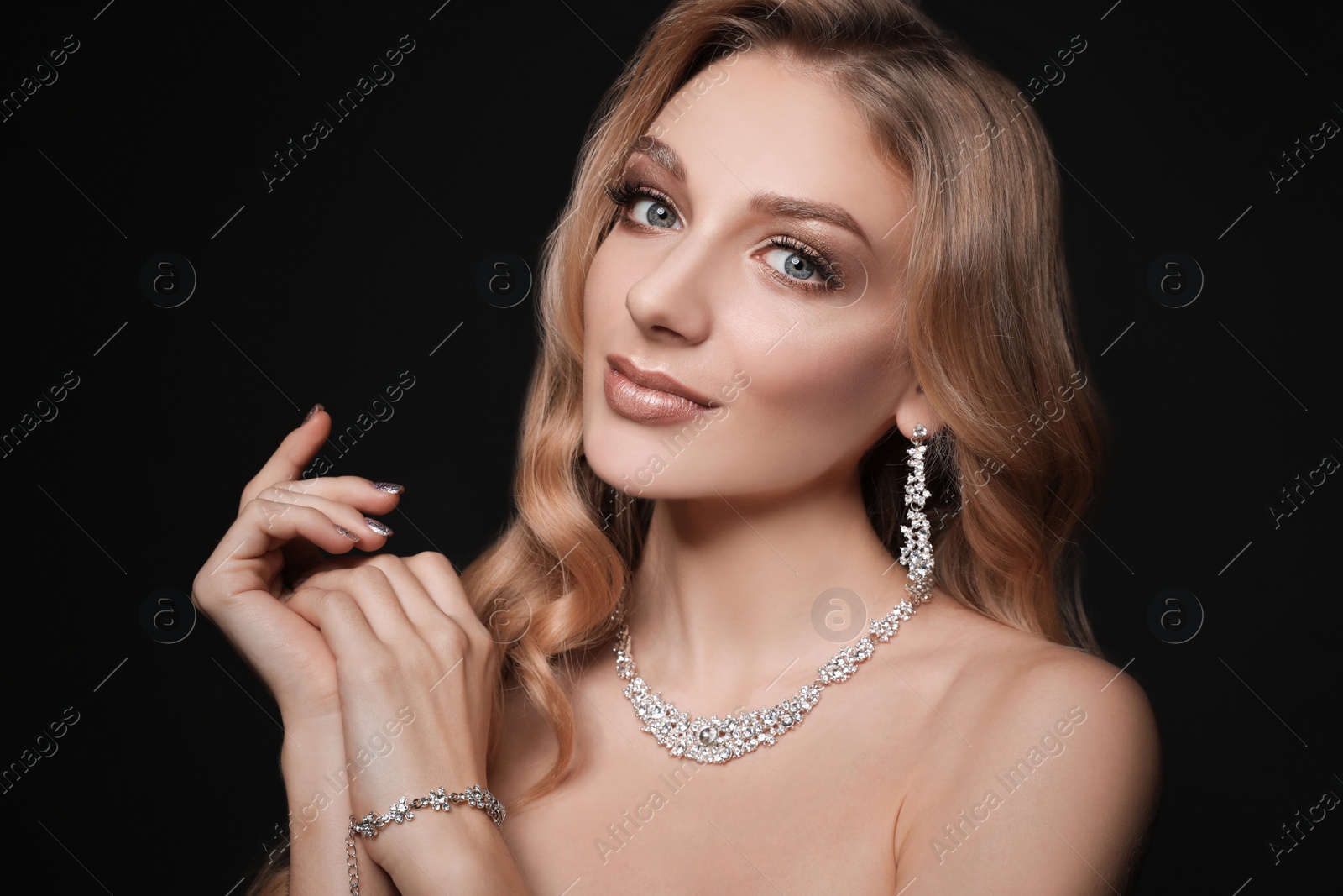 Photo of Beautiful young woman with elegant jewelry on dark background