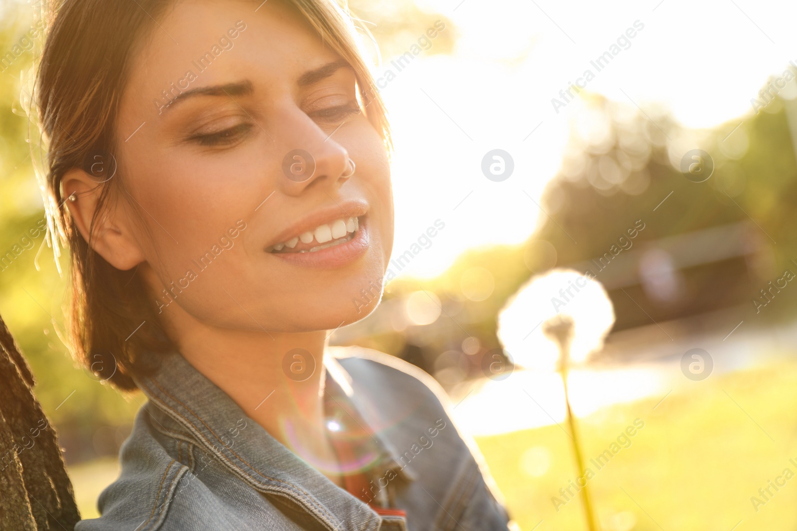 Photo of Young woman with dandelion in park on sunny day. Allergy free concept