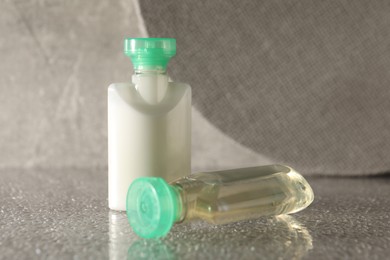 Mini bottles of cosmetic products on grey textured table