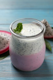 Photo of Tasty pitahaya smoothie, fruit and fresh mint on light blue wooden table