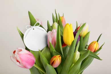 Photo of Bouquet of colorful tulips with blank card on white background, closeup