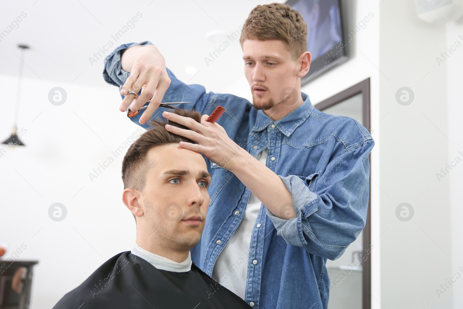 Photo of Professional barber working with client in hairdressing salon. Hipster fashion