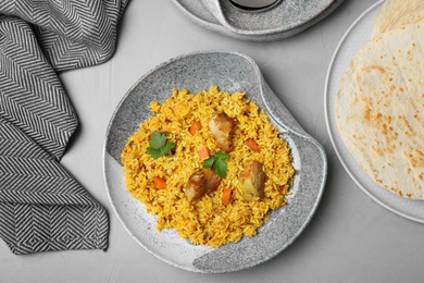 Plate of delicious rice pilaf and pita on grey table, flat lay