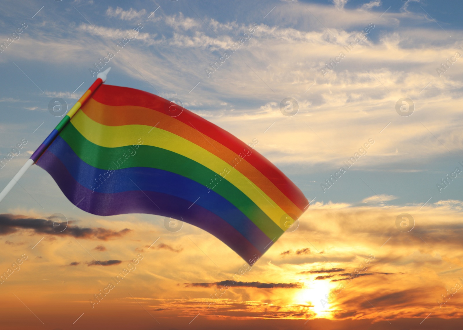Image of Bright rainbow LGBT flag against sky at sunset