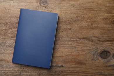 Photo of Blank blue passport on wooden table, top view with space for text