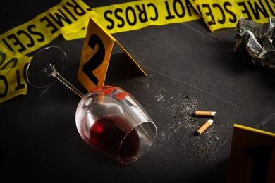 Photo of Wine glass with fingerprints and stubs on black slate table. Crime scene