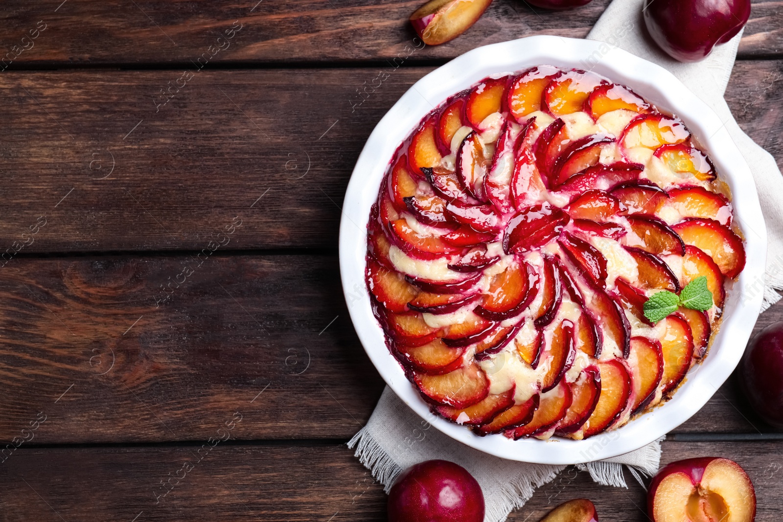 Photo of Delicious cake with plums on wooden table, flat lay. Space for text