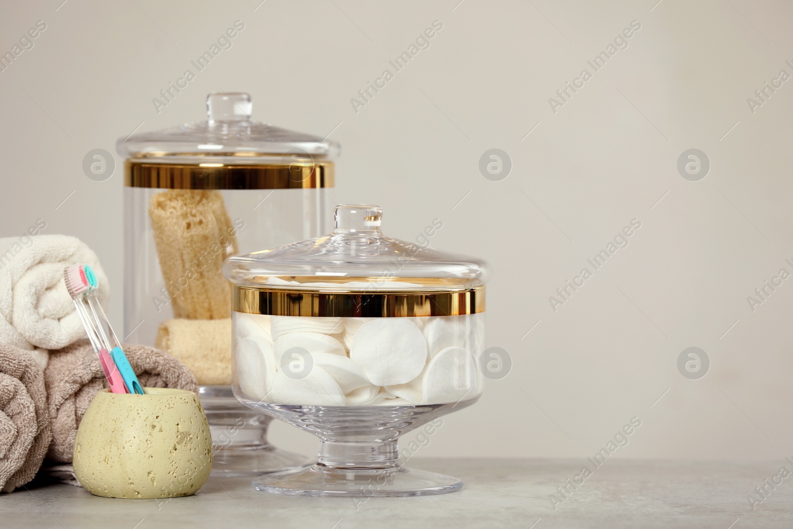 Photo of Composition of glass jar with cotton pads on table near light wall. Space for text