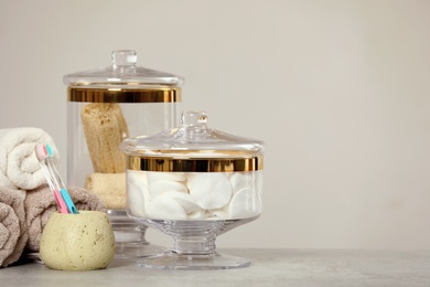 Photo of Composition of glass jar with cotton pads on table near light wall. Space for text