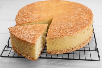 Tasty sponge cake on white wooden table, closeup