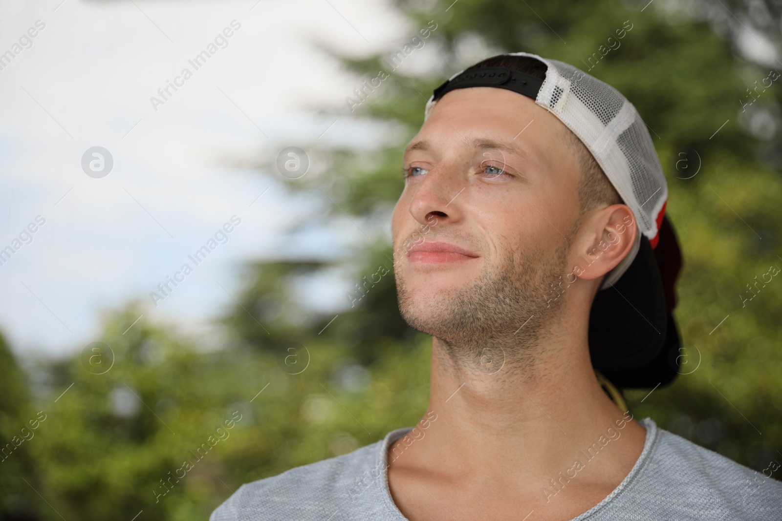 Photo of Handsome young man in stylish cap near reflection surface outdoors, space for text