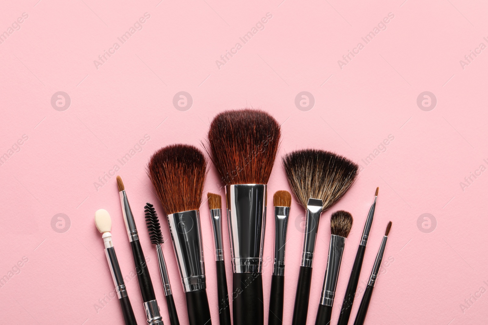 Photo of Different makeup brushes on pink background, flat lay. Space for text