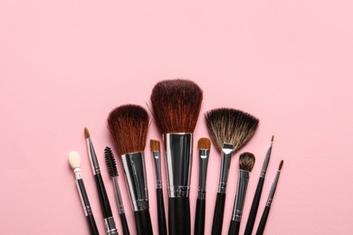 Photo of Different makeup brushes on pink background, flat lay. Space for text