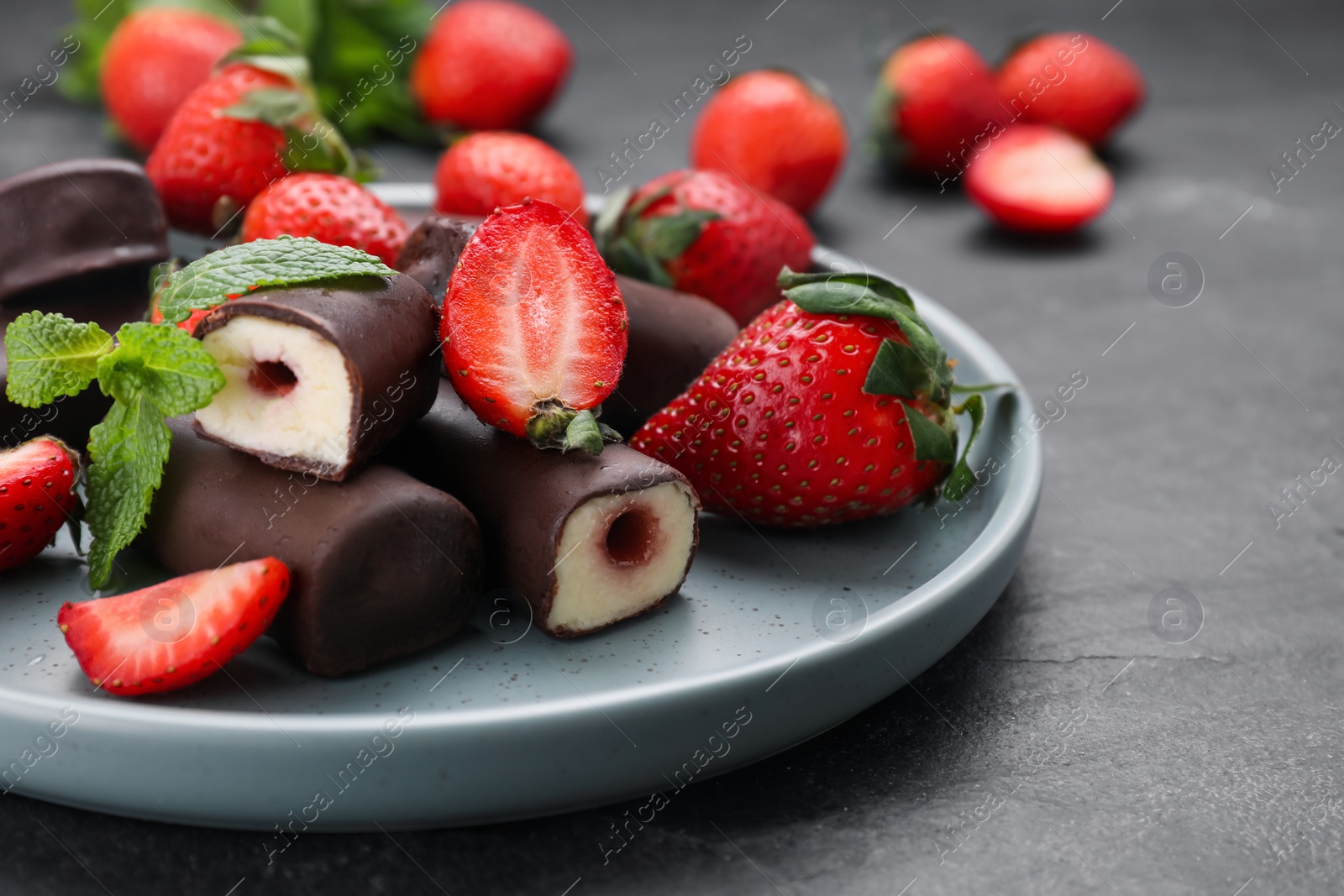 Photo of Delicious glazed curd snacks with fresh strawberries and mint on black table, closeup