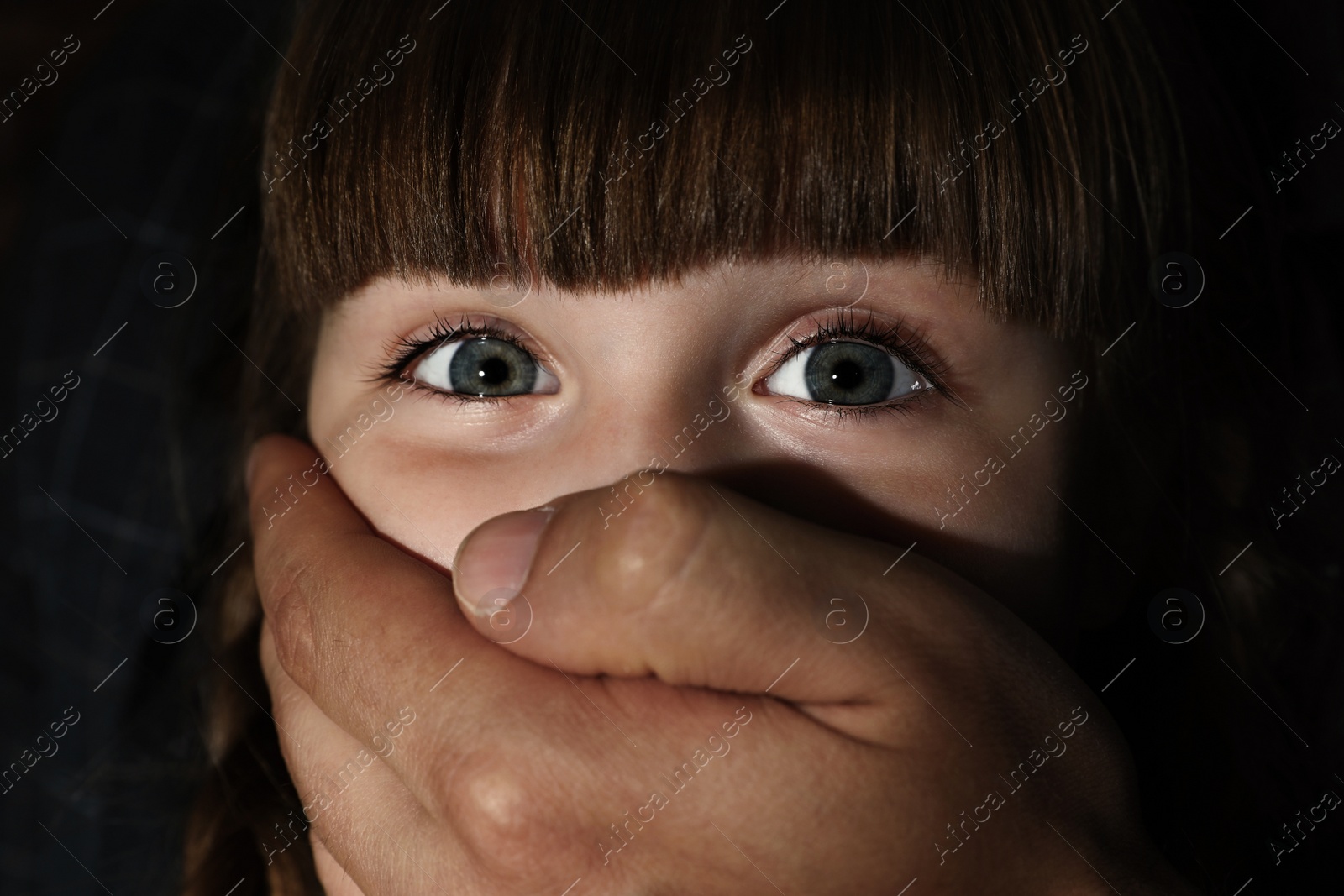 Photo of Adult man covering scared little girl's mouth, closeup. Child in danger