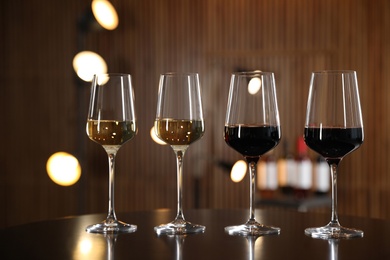 Glasses of different wines on table against blurred background