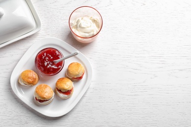 Photo of Tasty scones with clotted cream and jam on light background